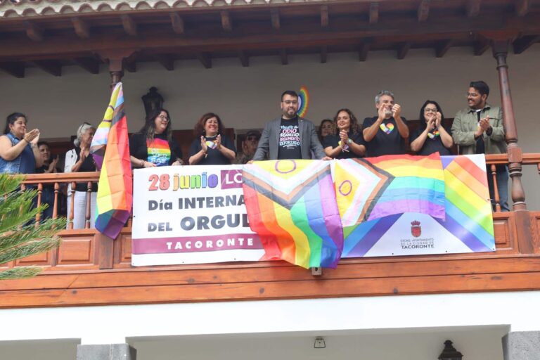 izado de bandera y fotografía junto a pancarta en balcón del Ayto