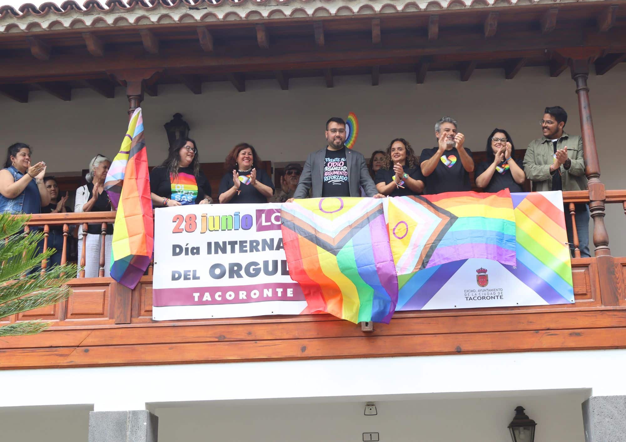 izado de bandera y fotografía junto a pancarta en balcón del Ayto